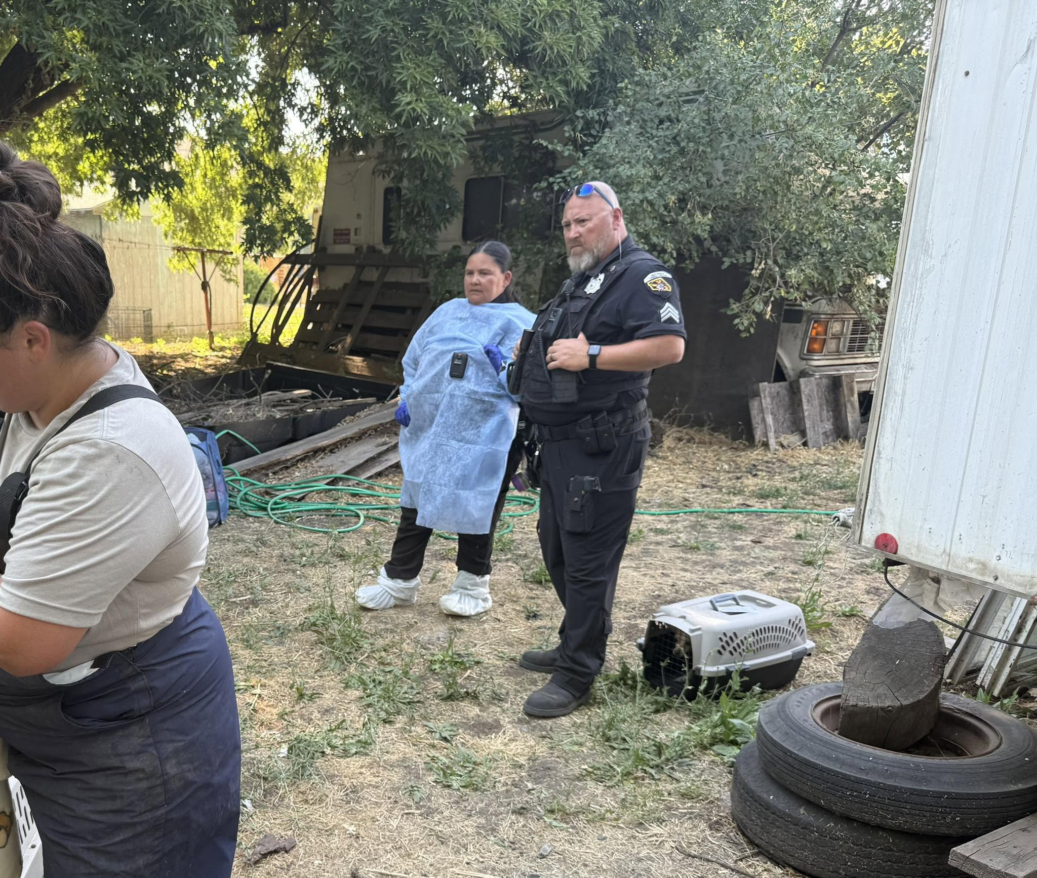 Animal rescue responders and a law enforcement officer at a property