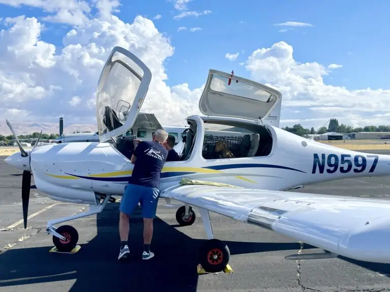 Person standing beside a small airplane with rescue dogs