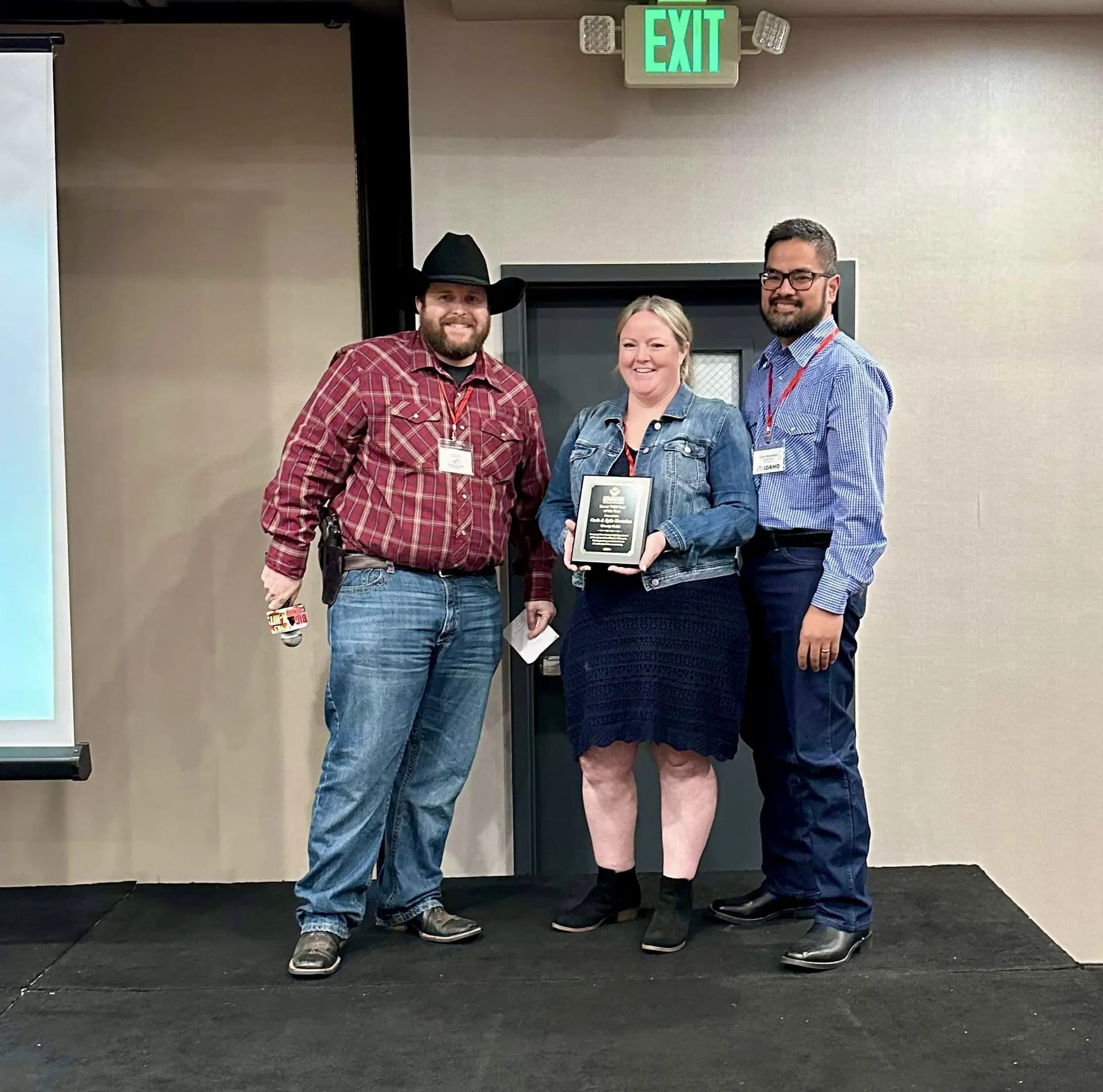 Three people holding an award plaque together