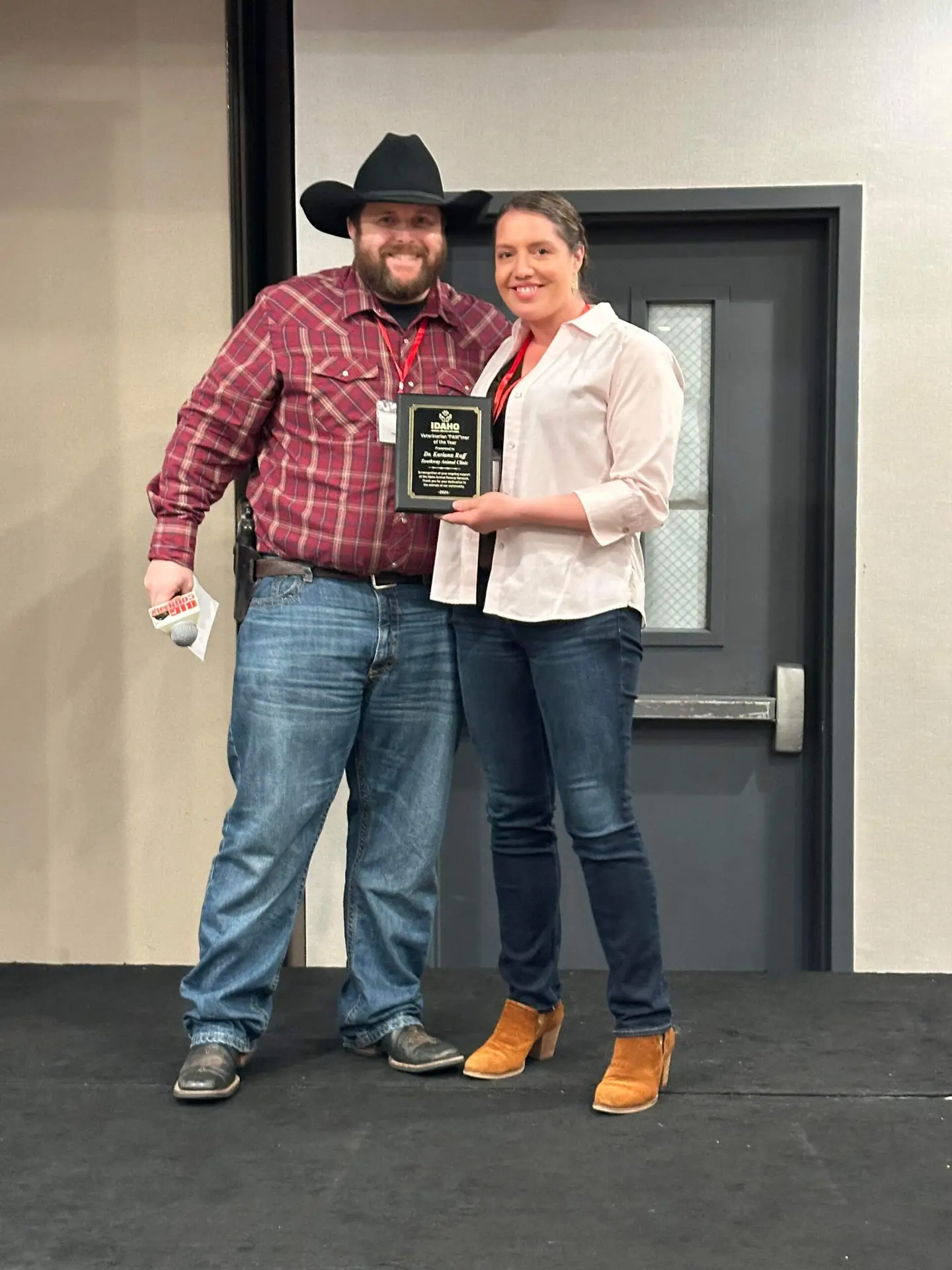 Two people celebrating with an award plaque